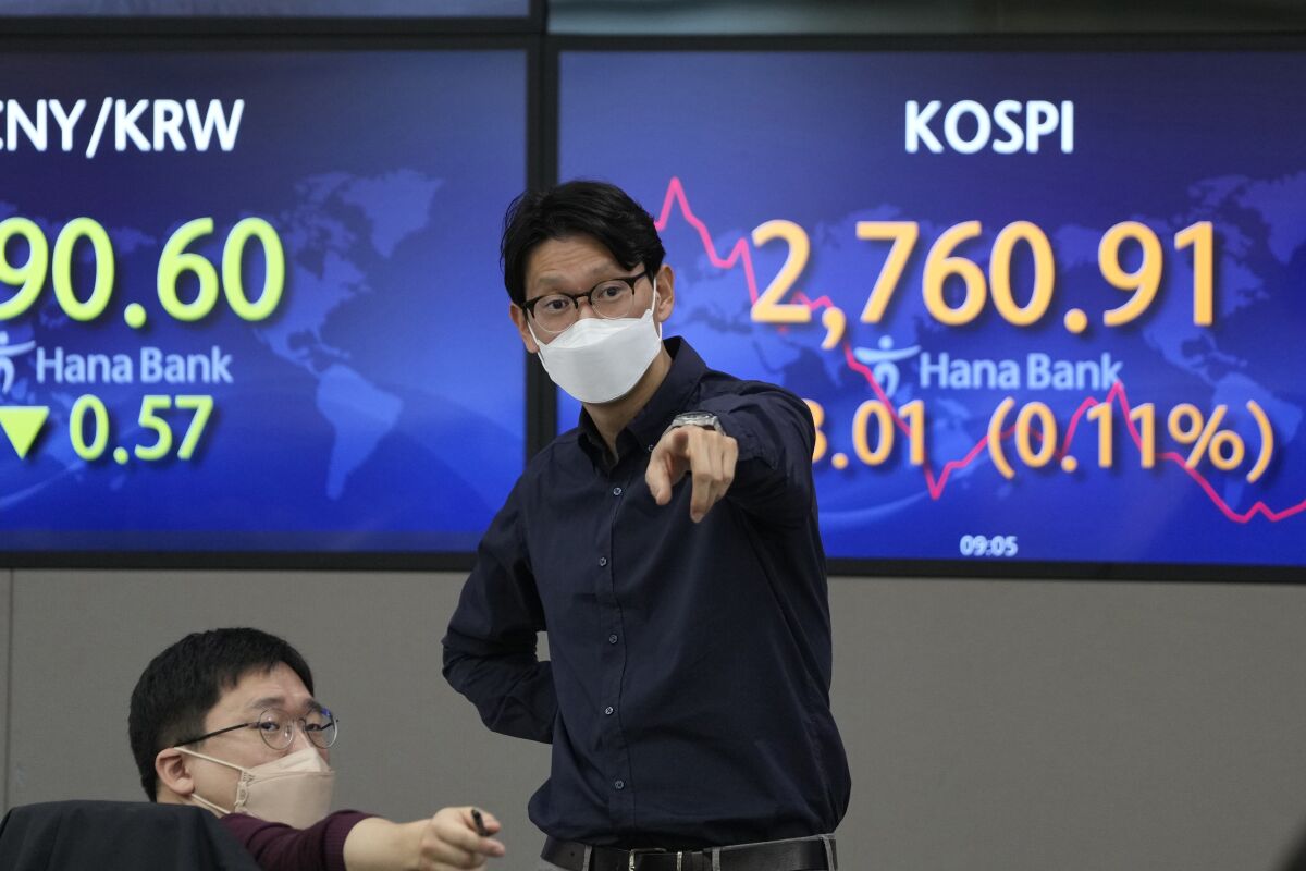 Currency traders gesture as they talk each others near the screens showing the Korea Composite Stock Price Index (KOSPI), right, at a foreign exchange dealing room in Seoul, South Korea, Tuesday, April 5, 2022. Shares fell Tuesday in Asia and oil prices advanced after a tech-driven rally on Wall Street. Trading was light with many regional markets including those in China closed for holidays. (AP Photo/Lee Jin-man)