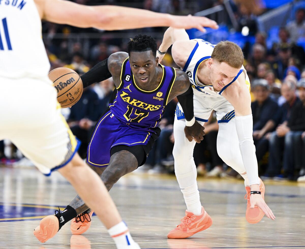Lakers guard Dennis Schroder, left, moves the ball past Golden State Warriors guard Donte DiVincenzo.