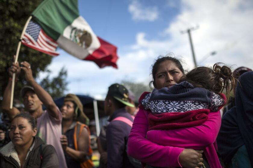 Honduran migrant Leticia Nunes holds her daughter Mailyn as she stands with a small group of other migrants in front of a line of Mexican police in riot gear, when they tried to cross the Chaparral border crossing in Tijuana, Mexico, Thursday, Nov. 22, 2018. The group of Central American migrants marched peacefully to the border crossing to demand better conditions and push to enter the U.S. (AP Photo/Rodrigo Abd)