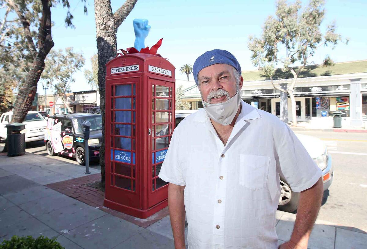 Laguna Beach artist Robert Holton stands next to his "Superhero Changing Station" on Forest Avenue.