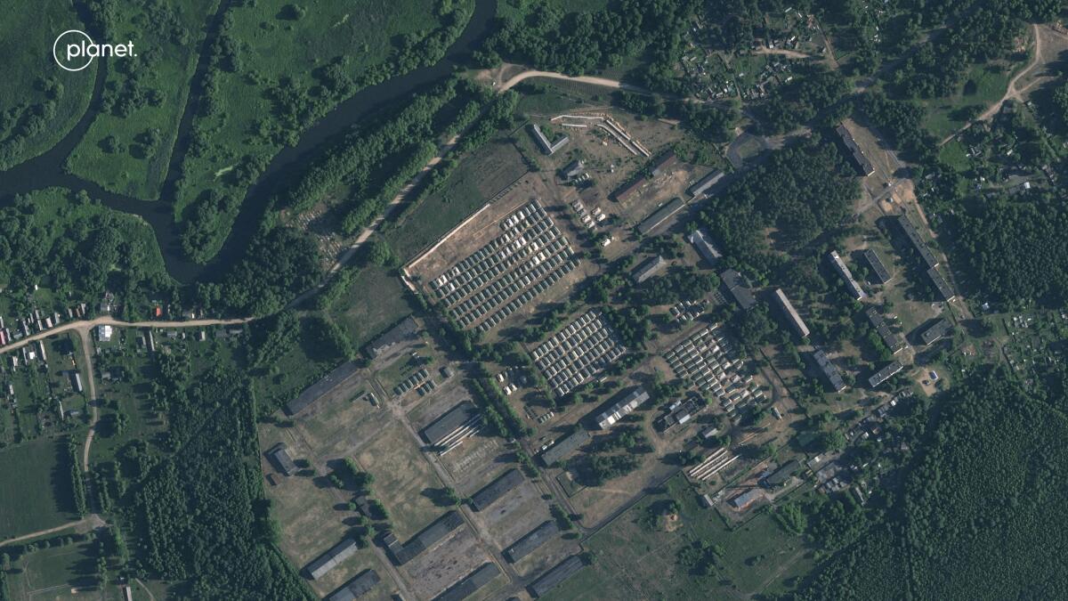 A satellite image shows apparent recent construction of tents at a former military base surrounded by countryside.