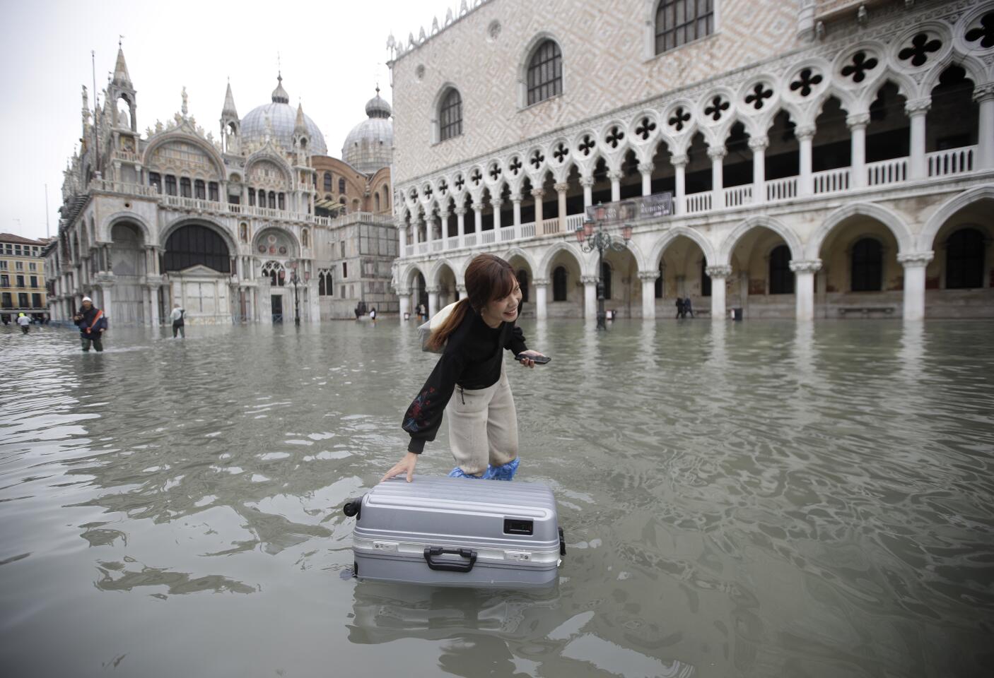A tourist pushes her floating luggage in a flooded St. Mark's Square in Venice.