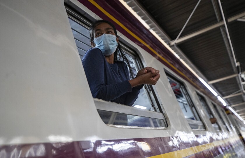 A passenger looks out from window on train bound for northeastern province of Ubon Ratchathani, at Hua Lamphong Railway Station in Bangkok, Thailand, Friday, April 9, 2021. Thai authorities were struggling Friday to contain a growing coronavirus outbreak just days before the country's traditional Songkran New Year's holiday, when millions of people travel around the country. (AP Photo/Sakchai Lalit)