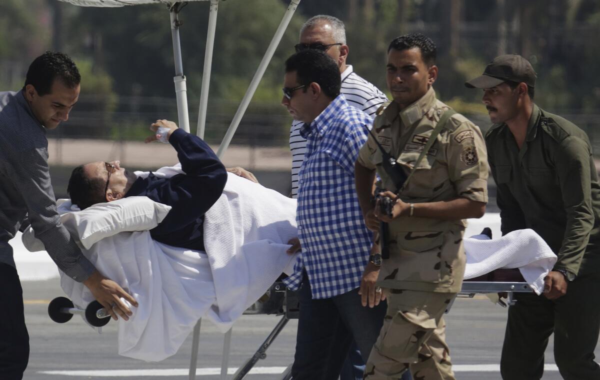 Medics and army personnel escort former Egyptian President Hosni Mubarak, 86, from a helicopter ambulance after landing at the Maadi Military Hospital following his appearance Aug. 13 in a Cairo court.