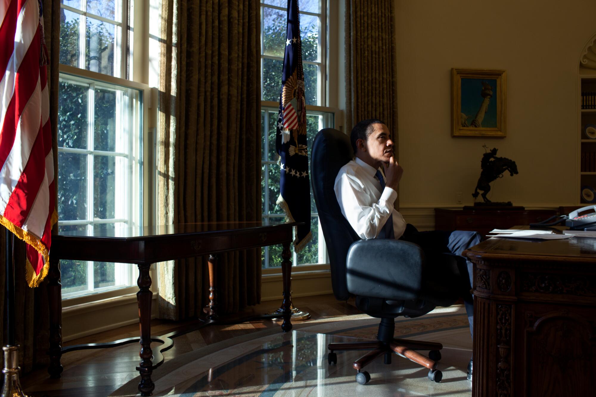 President Barack Obama sits in the Oval Office on his first day in office, Jan. 21, 2009.