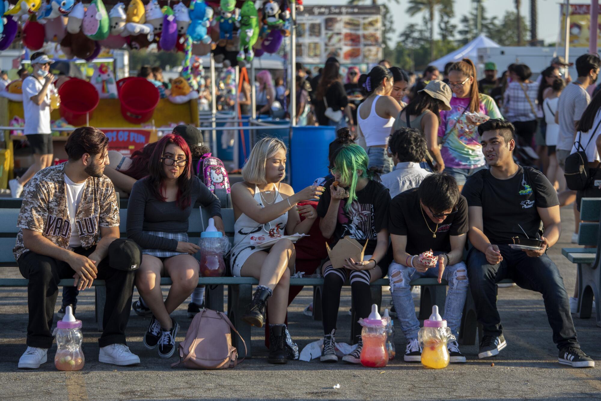 Patrons sit on a bench to eat at the 626 Night Market 