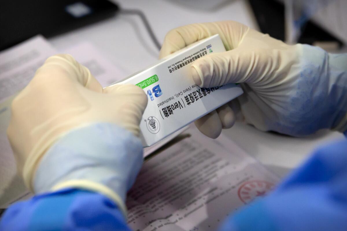 A worker opens a package of COVID-19 vaccine at a vaccination center in Beijing.