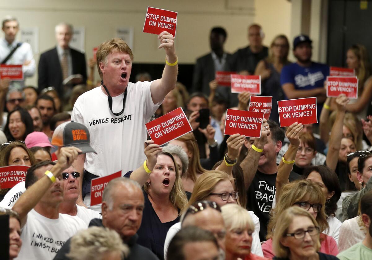 People hold up signs during a public meeting