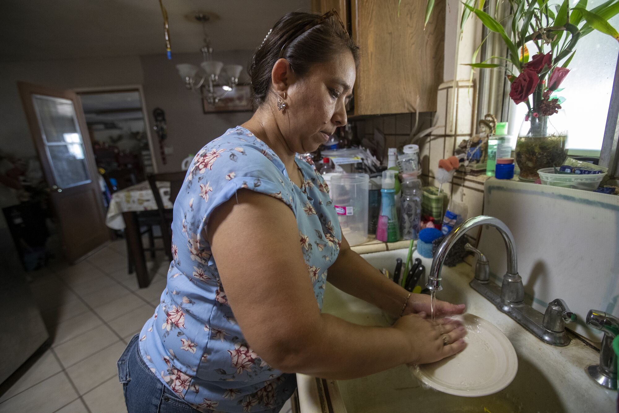 A woman washes dishes in the kitchen sink