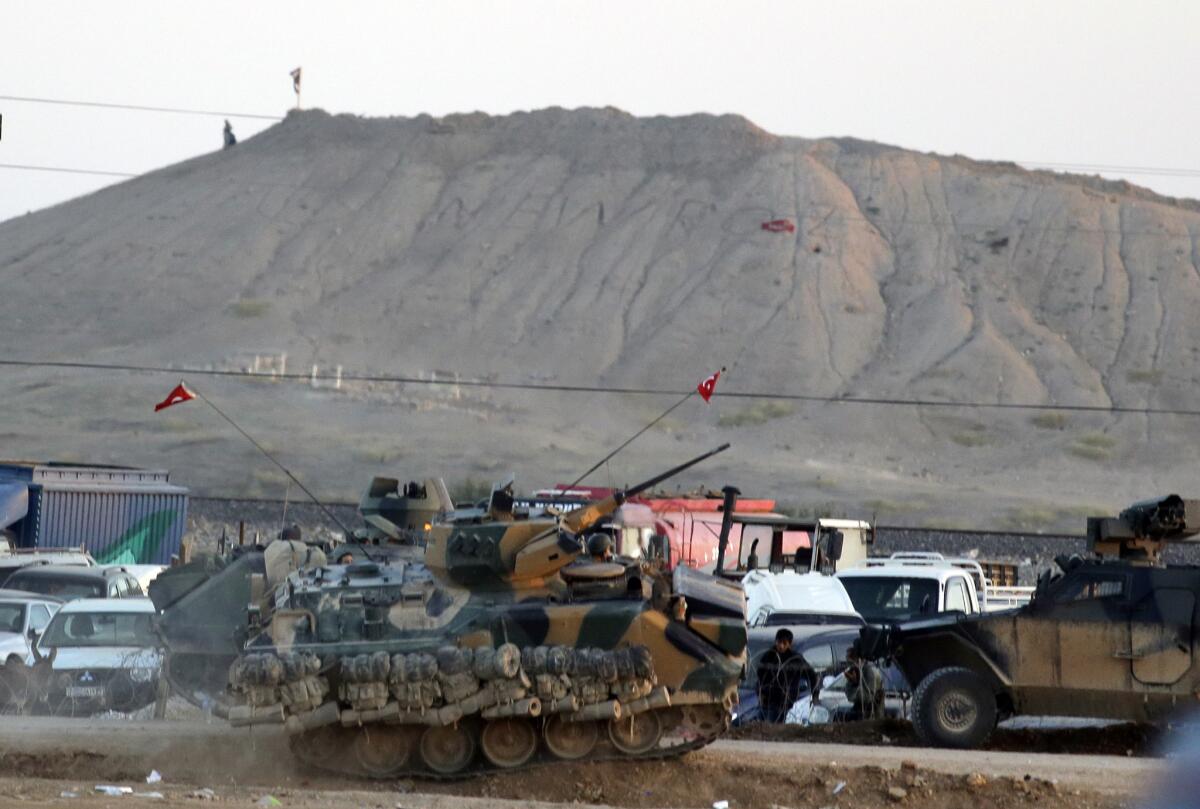 Turkish forces secure the border at Surac as militants with the Islamic State place their group's flag on a hilltop at the eastern side of the nearby town of Kobani, Syria, on Oct. 6