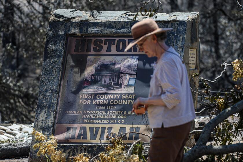 Havilah, CA, Tuesday, July 30, 2024 - Havilah resident and historical society member Janet Kutzner passes by the remains of the town's museum days after the Borel Fire razed much of the historic mining town. Robert Gauthier/Los Angeles Times)