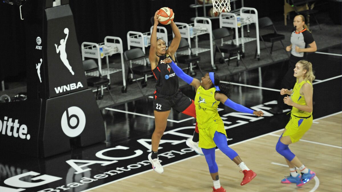 Las Vegas Aces' A'ja Wilson (22) grabs a rebound from Dallas Wings' Tyasha Harris, center, as Bella Alarie, right, watches during the first half of a WNBA basketball game Sunday, Aug. 2, 2020, in Bradenton, Fla. (AP Photo/Steve Nesius)