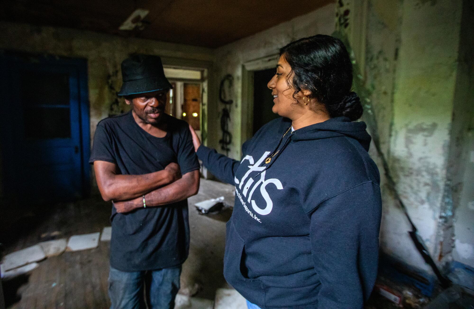 A man and woman stand in a room of an abandoned property.