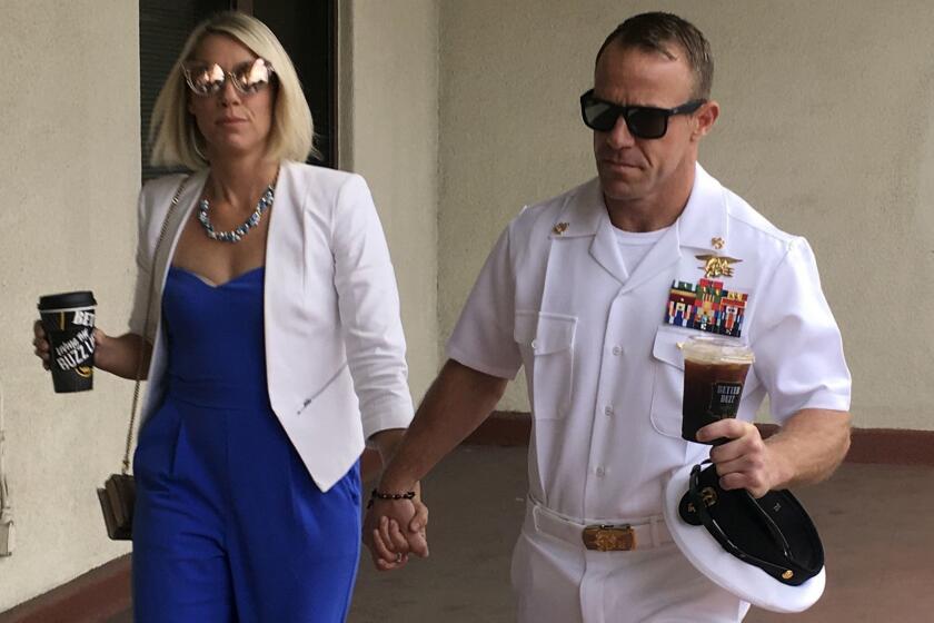 Navy Special Operations Chief Edward Gallagher, right, walks with his wife, Andrea Gallagher as they arrive to military court on Naval Base San Diego, Wednesday, June 26, 2019, in San Diego. Trial continues in the court-martial of the decorated Navy SEAL, who is accused of stabbing to death a wounded teenage Islamic State prisoner and wounding two civilians in Iraq in 2017. He has pleaded not guilty to murder and attempted murder, charges that carry a potential life sentence. (AP Photo/Julie Watson)