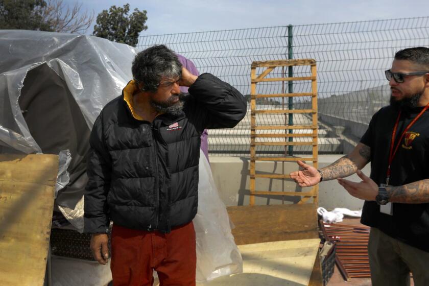 COMPTON, CA APRIL 6, 2018: Adrian Tafoya, right, with HOPICS (Homeless Outreach Program Integrated Care System) talks with Jesus (no last name) left, in Compton, CA April 6, 2018. Jesus has constructed a hovel he is living in. HOPICS outreach workers are trying to cox him to go with them. Jesus would not go and ended up leaving the area. In Los Angeles County, the Department of mental Health had accumulated nearly $900 million. Advocates say much of this money could have put crisis teams on the street, started construction on supportive housing projects and funded psychiatric urgent care centers. (Francine Orr/ Los Angeles Times)