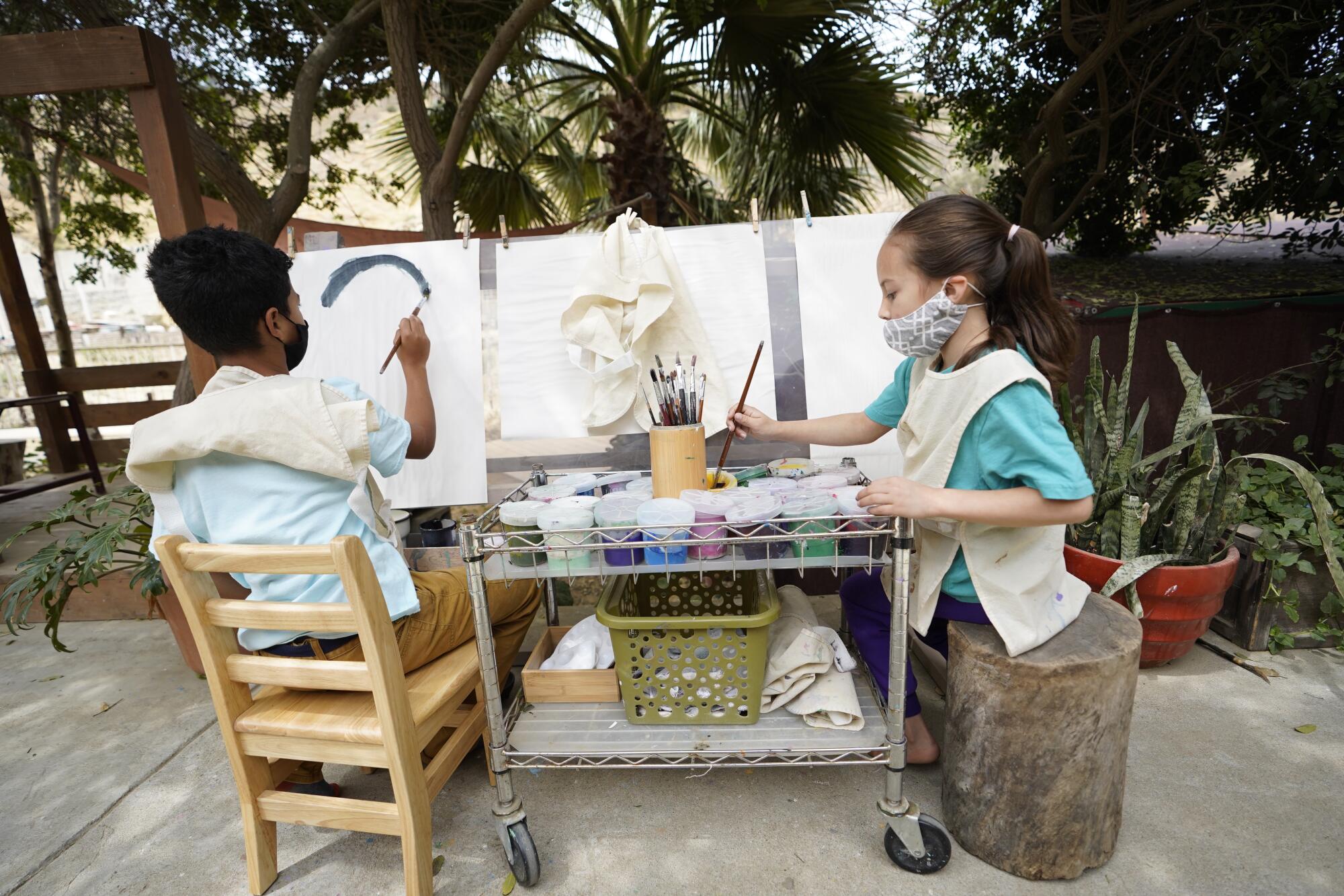Dos niños pintan para hacer obras de arte.
