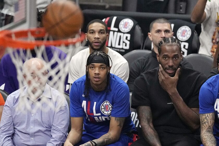 Los Angeles Clippers forward Kawhi Leonard, right, watches from the bench during the first half.