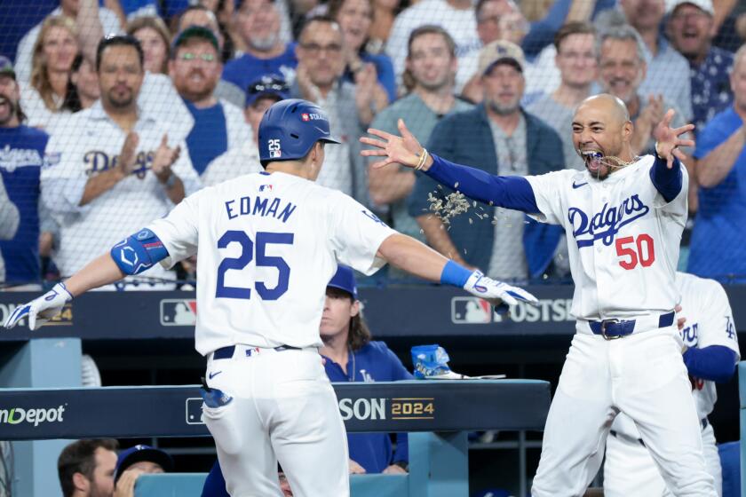 LOS ANGELES, CALIFORNIA - OCTOBER 20: Mookie Betts #50 of the Los Angeles Dodgers throws sunflower seeds on Tommy Edman #25 after Edman hit a two-run home run during the third inning in game six of the National League Championship Series against the New York Mets at Dodger Field on Sunday, Oct. 20, 2024 in Los Angeles. (Wally Skalij / Los Angeles Times)