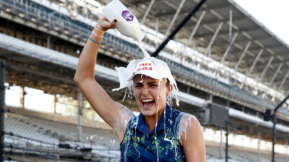 Lexi Thompson pours milk on her head while standing on the race track at the Indianapolis Motor Speedway after winning the Indy Women In Tech Championship on Saturday.
