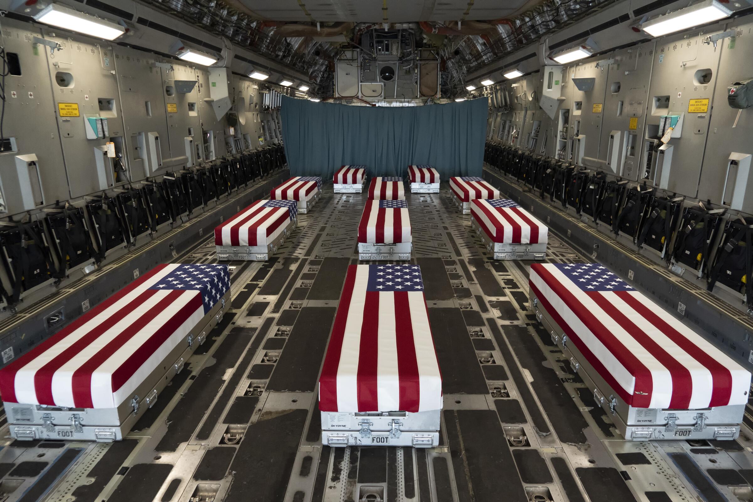 Image provided by the U.S. Air Force, flag-draped transfer cases line the inside of a transport plane.