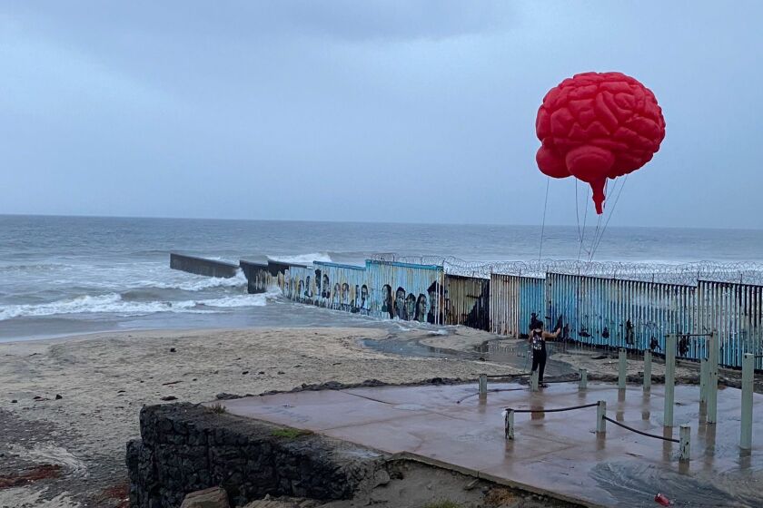 Alejandro Rocha, 36, sobrevuela un cerebro rojo de helio frente al muro fronterizo en Playas de Tijuana