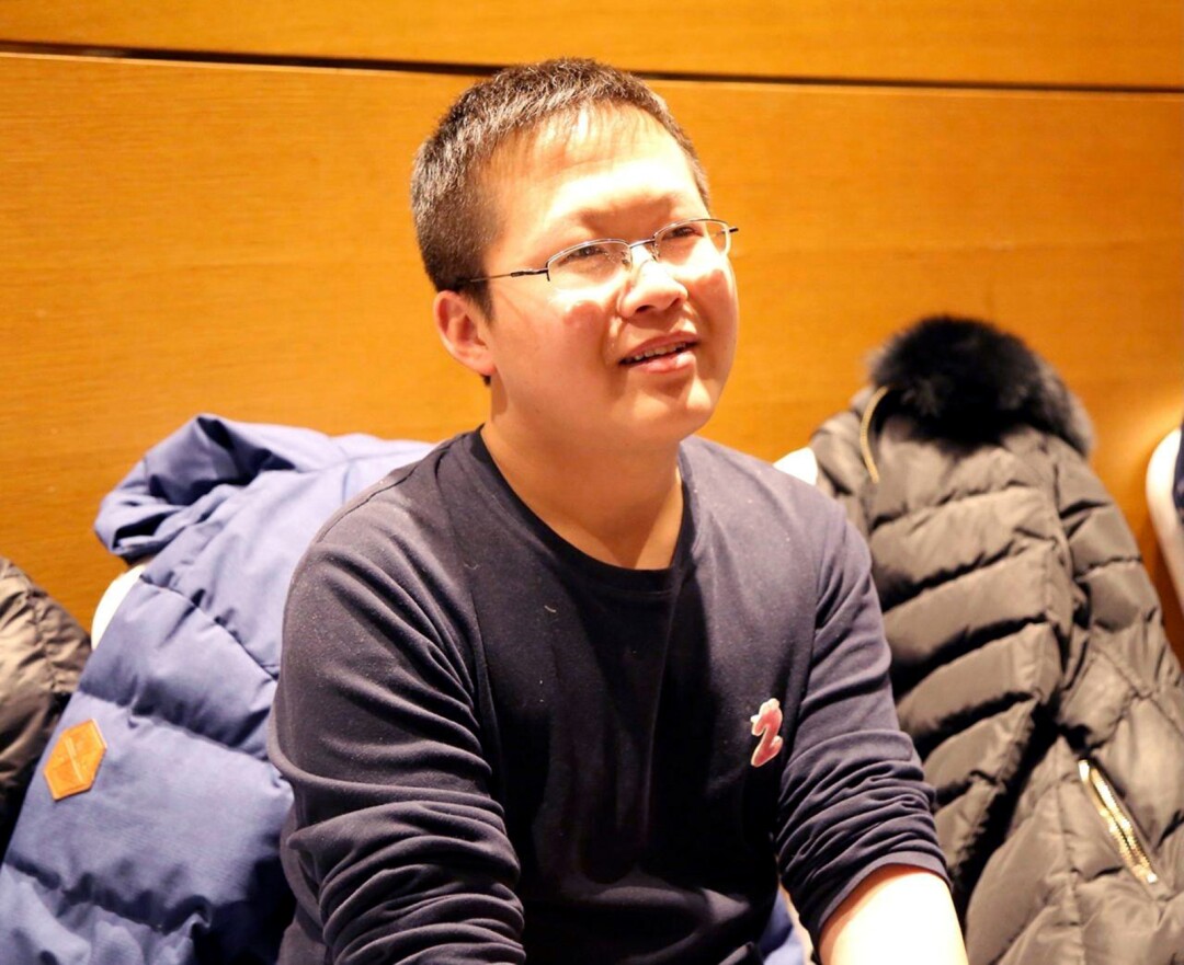 A man in glasses sits amid puffer coats