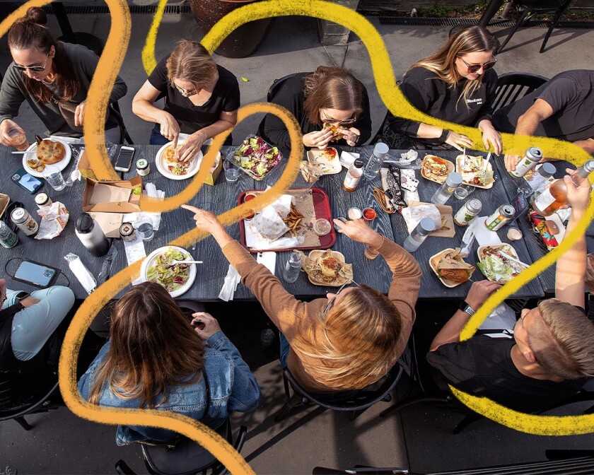 An aerial shot of people sitting a table eating food.
