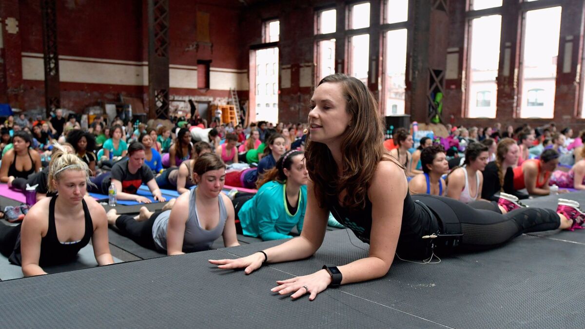 Cara Gilman wears a Fitbit tracker as she leads a yoga workout in Boston. A new study assessing four wristband fitness trackers found that none of them were good at tracking heart rate when users were moving while exercising.