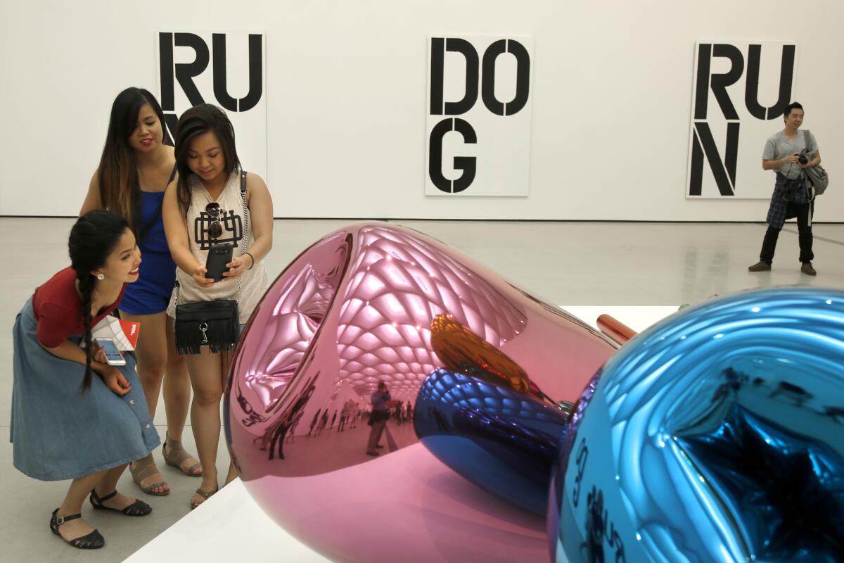 Celia Tran of West Covina, Kathy Tran of Glendale and Dee Tran of El Monte take a photograph in the reflection of Jeff Koons' "Tulips" at the Broad.