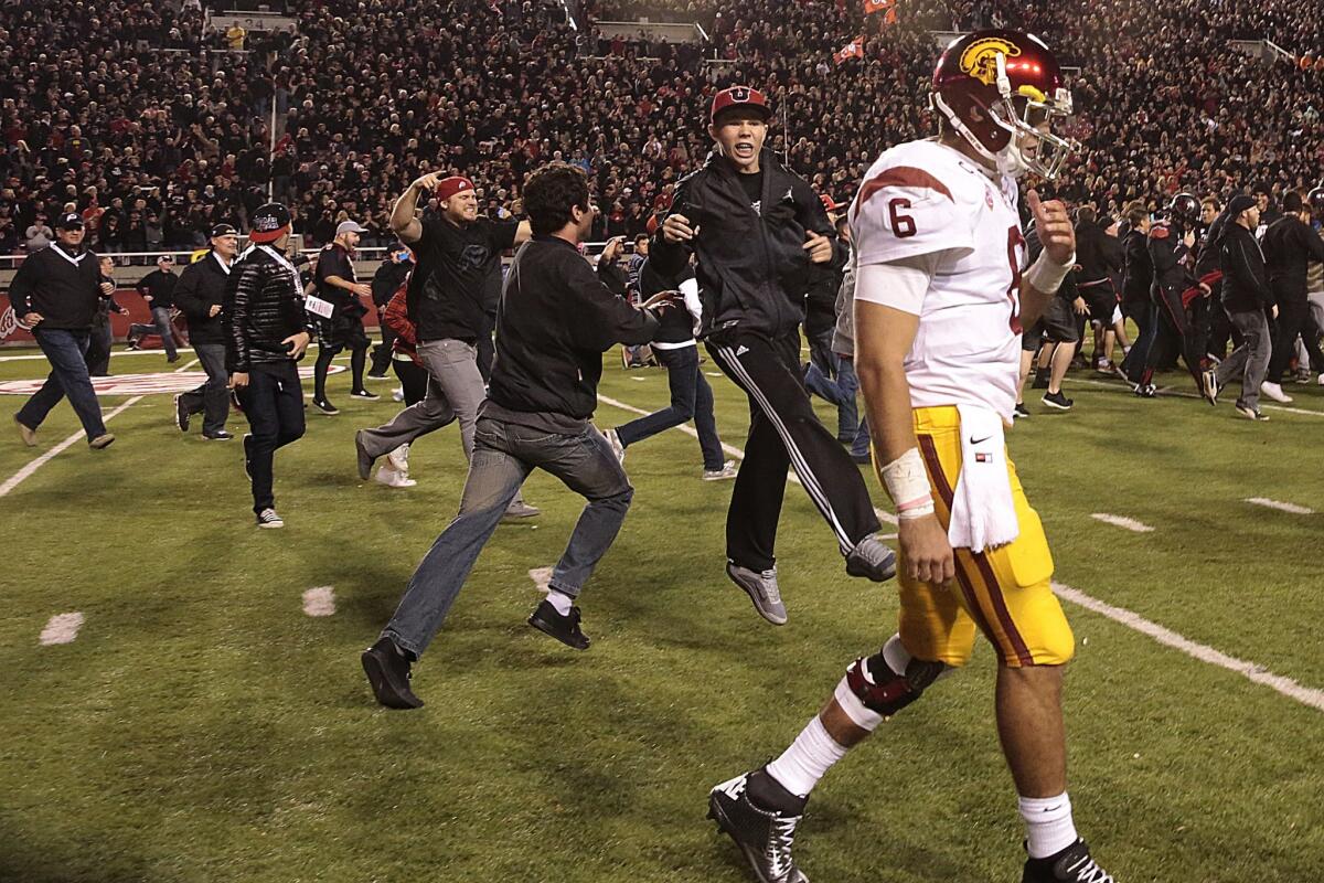 Trojans quarterback Cody Kessler leaves the field as Utes fans celebrate Utah's 24-21 victory.