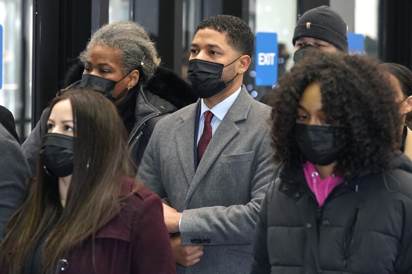 A group of people standing in suits, coats and face masks