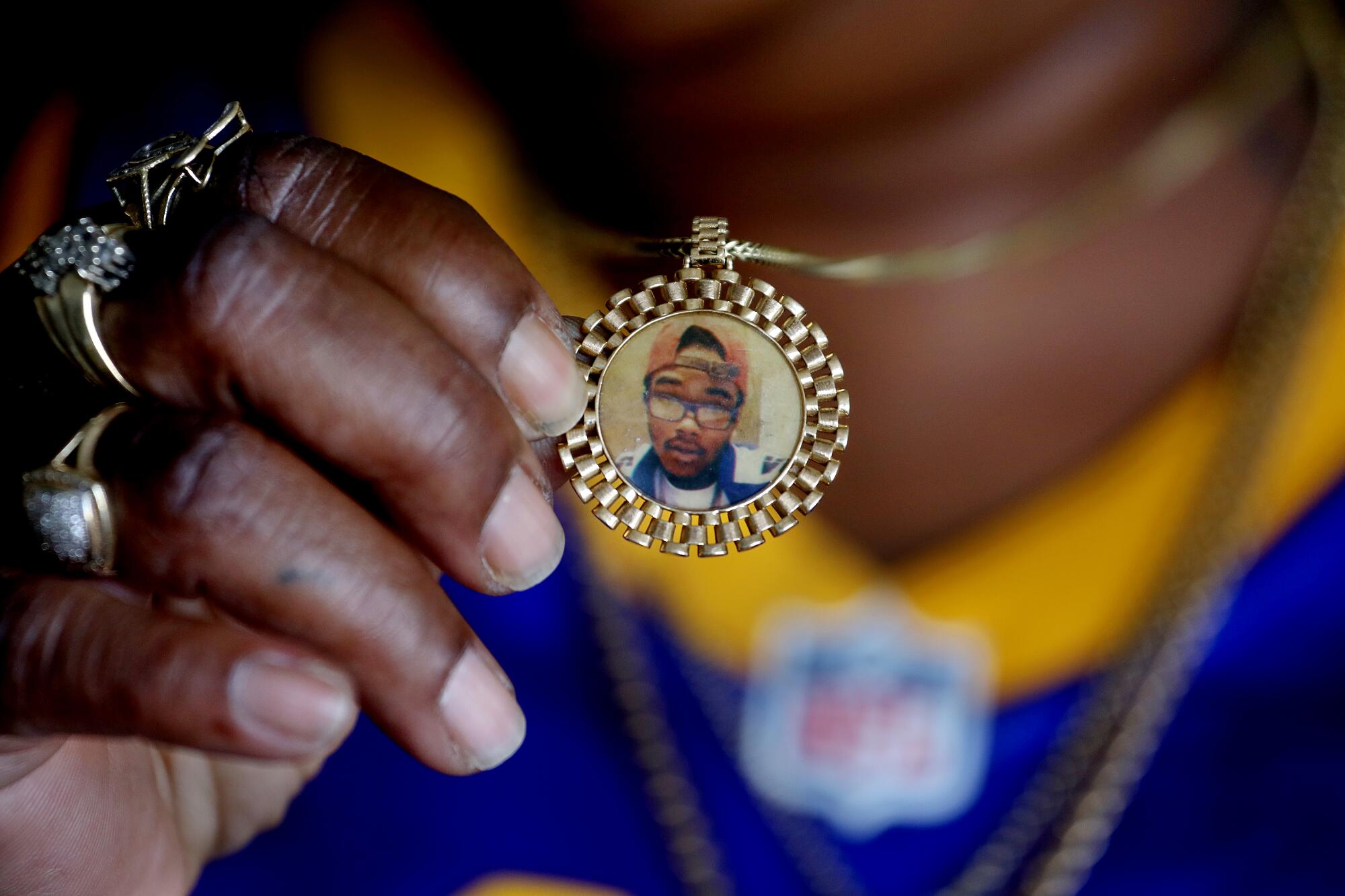 Latasha Bracks holds a necklace bearing the image of her son