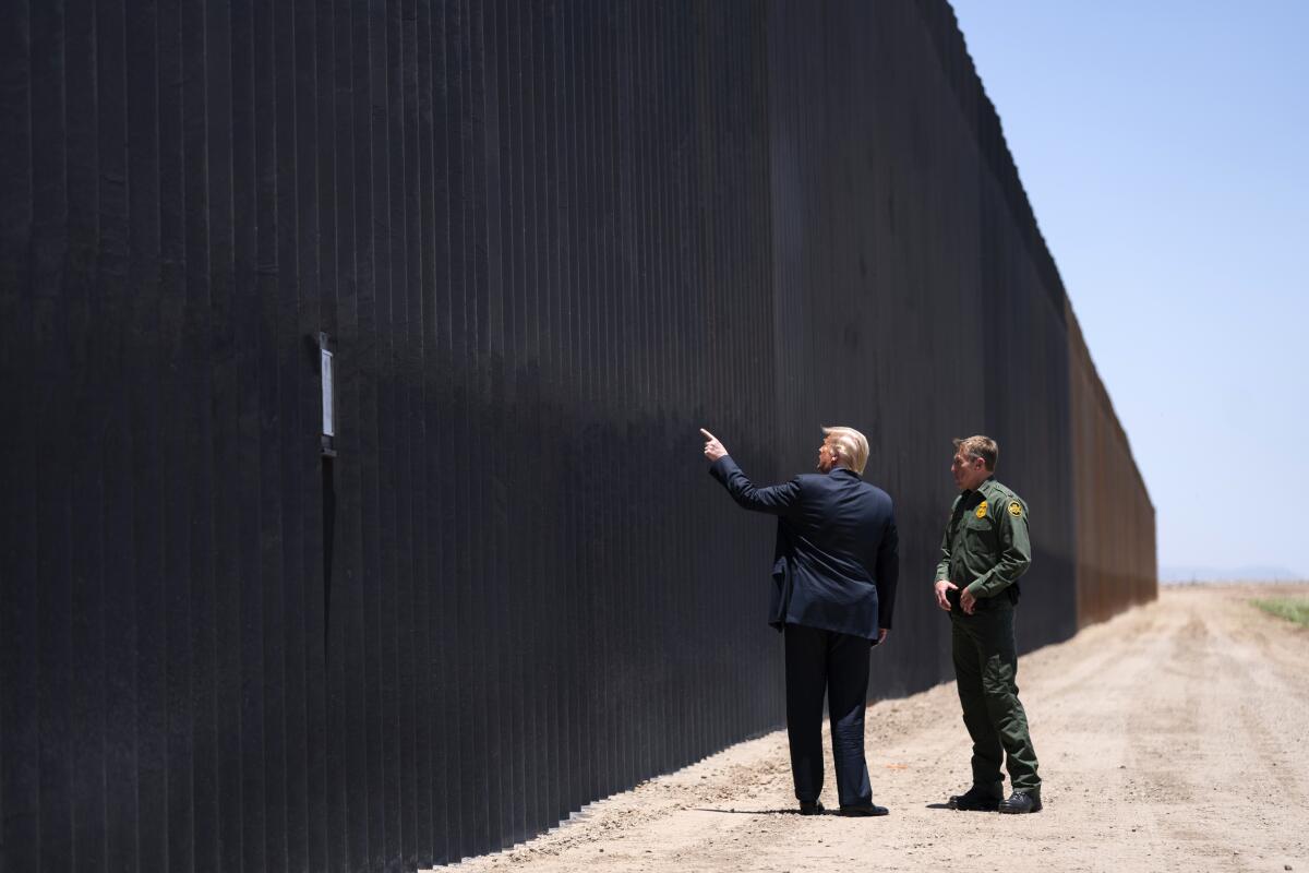 El presidente Donald Trump habla con Rodney Scott, mientras recorre una sección del muro fronterizo en San Luis, Arizona.