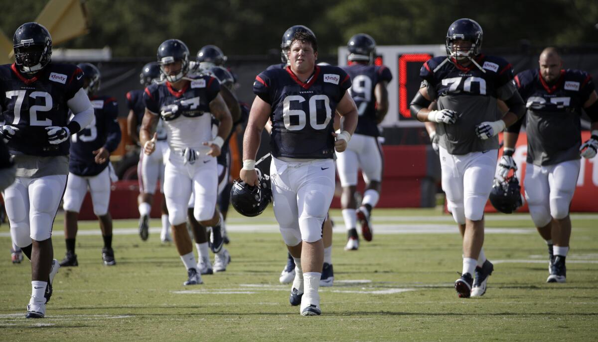 Houston's Ben Jones (60) warms up with teammates during training camp on Aug. 5.