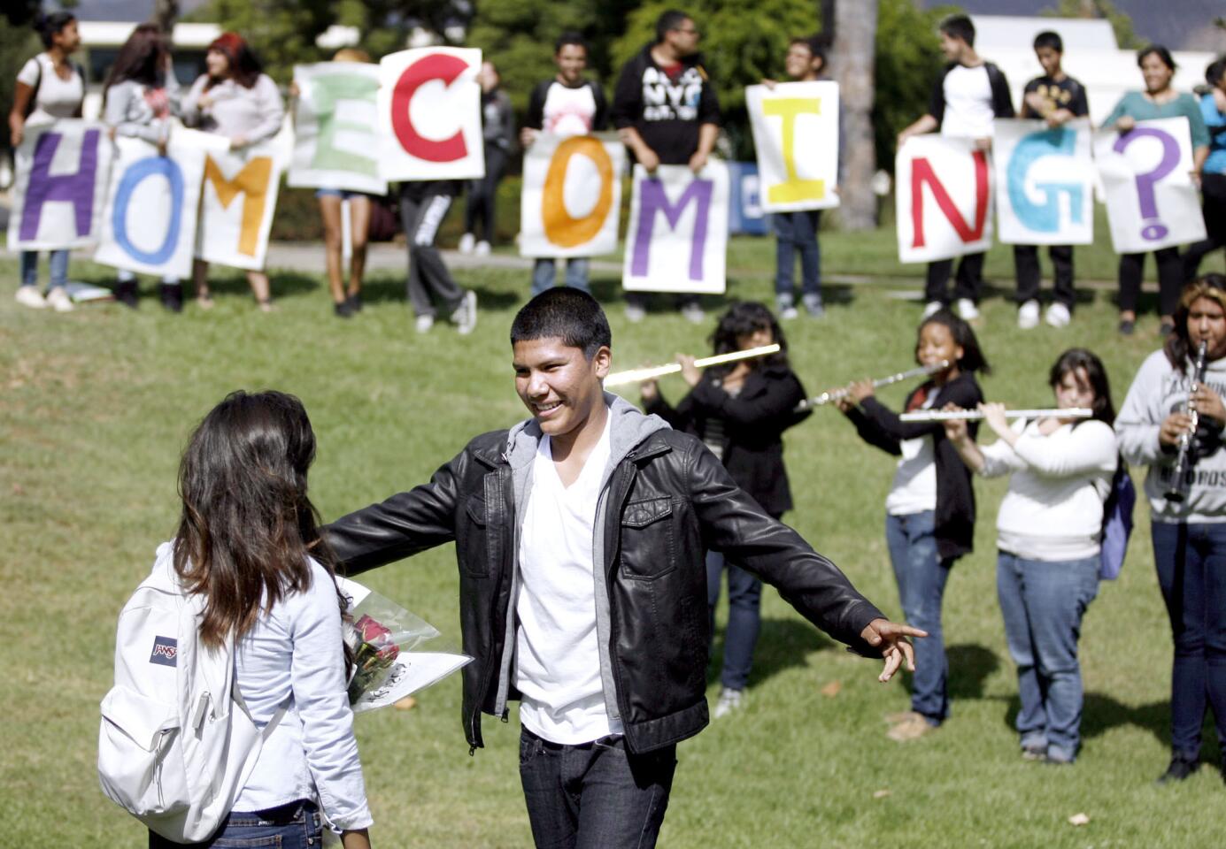 With Journey's "Don't Stop Believing" played by some band members in the background, Muir High School freshman Abraham Romero, 14, brought some friends along for encouragement as he asked freshman Michelle Rios, 14, out to the school's Homecoming, during lunch at the Pasadena school on Wednesday, Oct. 10, 2012. The moment she said yes, Romero spread his arms in delight and gave Rios a big hug. Romero's sister made the signs in the background, friends helped hold them up and some of the band members came along to play.