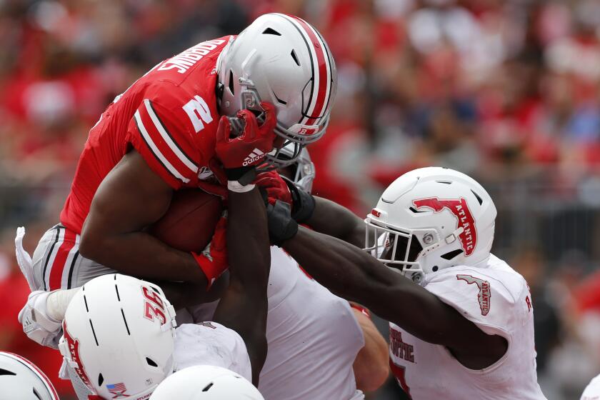 Ohio State running back J.K. Dobbins, top, leaps over Florida Atlantic defenders Akileis Leroy, left, and Rashad Smith for a touchdown during the second half of an NCAA college football game Saturday, Aug. 31, 2019, in Columbus, Ohio. Ohio State beat Florida Atlantic 45-21. (AP Photo/Jay LaPrete)