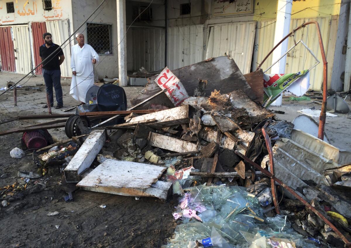 Civilians inspect the aftermath of a car bomb explosion in Baghdad on Oct. 18. During the day Iraqi lawmakers approved Prime Minister Haider Abadi's choices to fill two key security posts to combat violence in the country, those of interior and defense ministers.