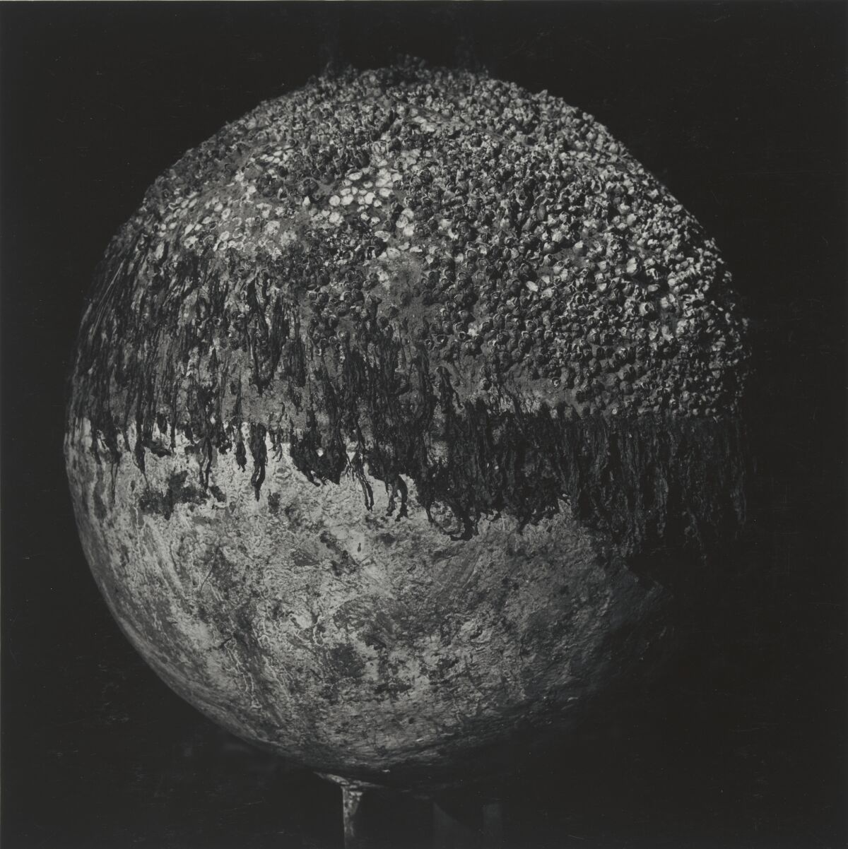 An abstracted black and white photograph depicts a sphere with gritty textures.