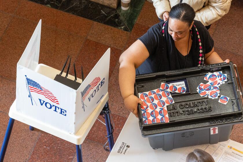 Los Angeles, CA - March 05: A poll worker moves a ballot box as voters to arrive and cast ballots inside the cavernous lobby of the Metro Headquarters Building on Tuesday, March 5, 2024 in Los Angeles, CA. (Brian van der Brug / Los Angeles Times)