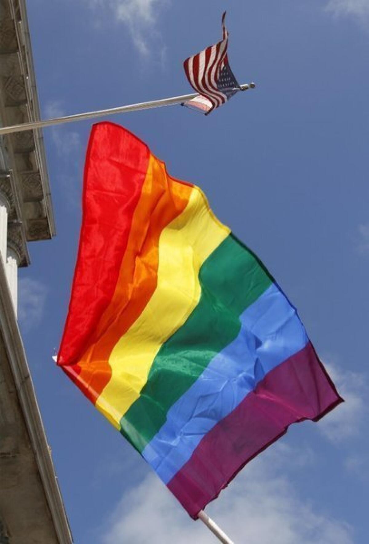 A rainbow flag flies below the American flag outside City Hall in San Francisco.