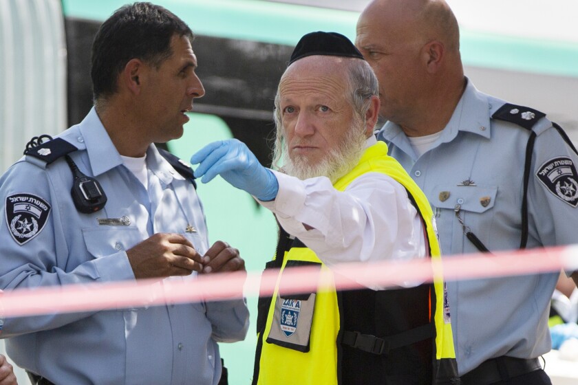 FILE - Yehuda Meshi-Zahav, then head of Israel's ZAKA rescue service, center, stands at the scene of a shooting attack by a Palestinian gunman, in Jerusalem on Oct. 13, 2015. Meshi-Zahav, a prominent member of Israel’s ultra-Orthodox community who long served as a symbol of coexistence before his reputation came crashing down in a series of sexual abuse allegations, has died. Jerusalem’s Herzog Medical Center confirmed his death on Wednesday, June 29, 2022, but did not give a cause. He was 62. (AP Photo/Oded Balilty, File)