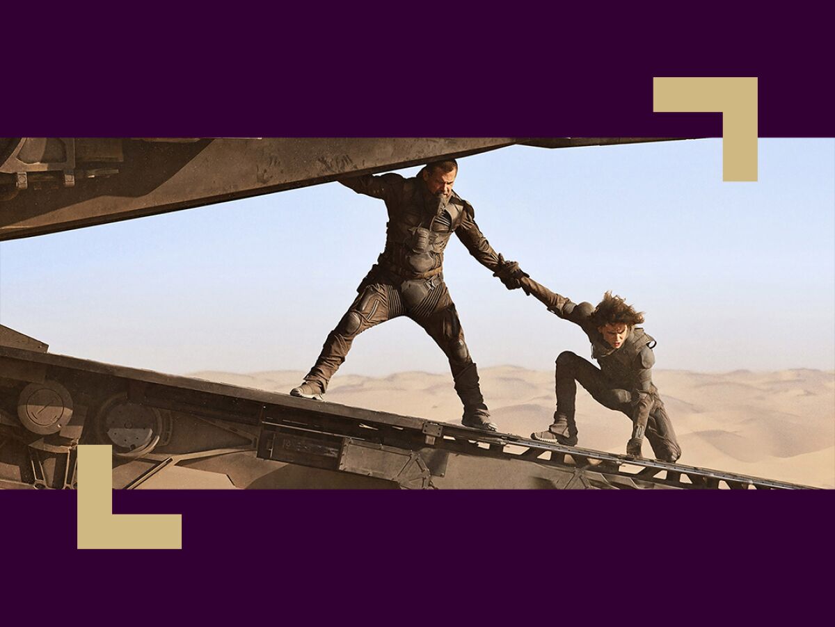 A man grabs another man's arm for balance on a loading dock in a desert scene.