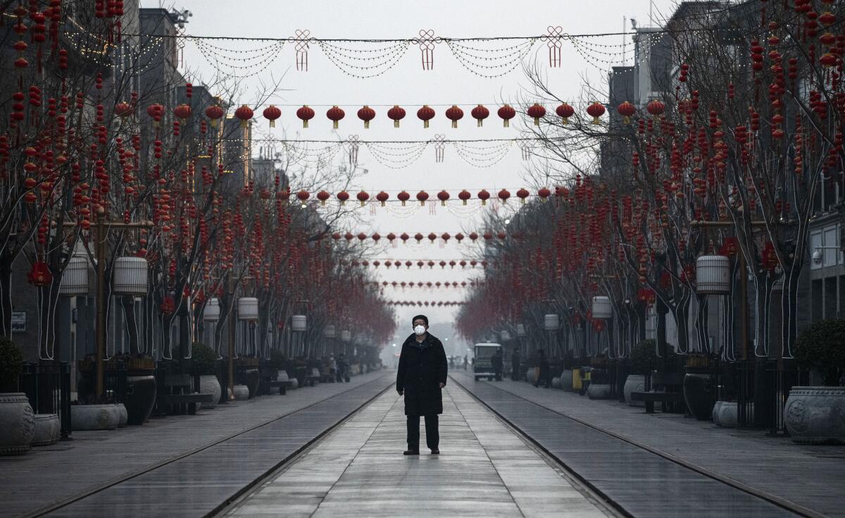 A man walks on a nearly empty and shuttered commercial street in Beijing in February 2020.