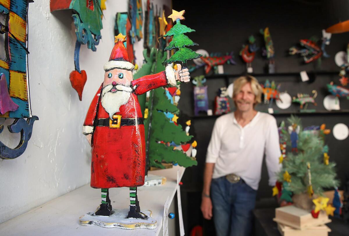 Woodworking artist Nikolai Erngren with one of his bright Santa Claus pieces at the Sawdust Art Festival Winter Fantasy.
