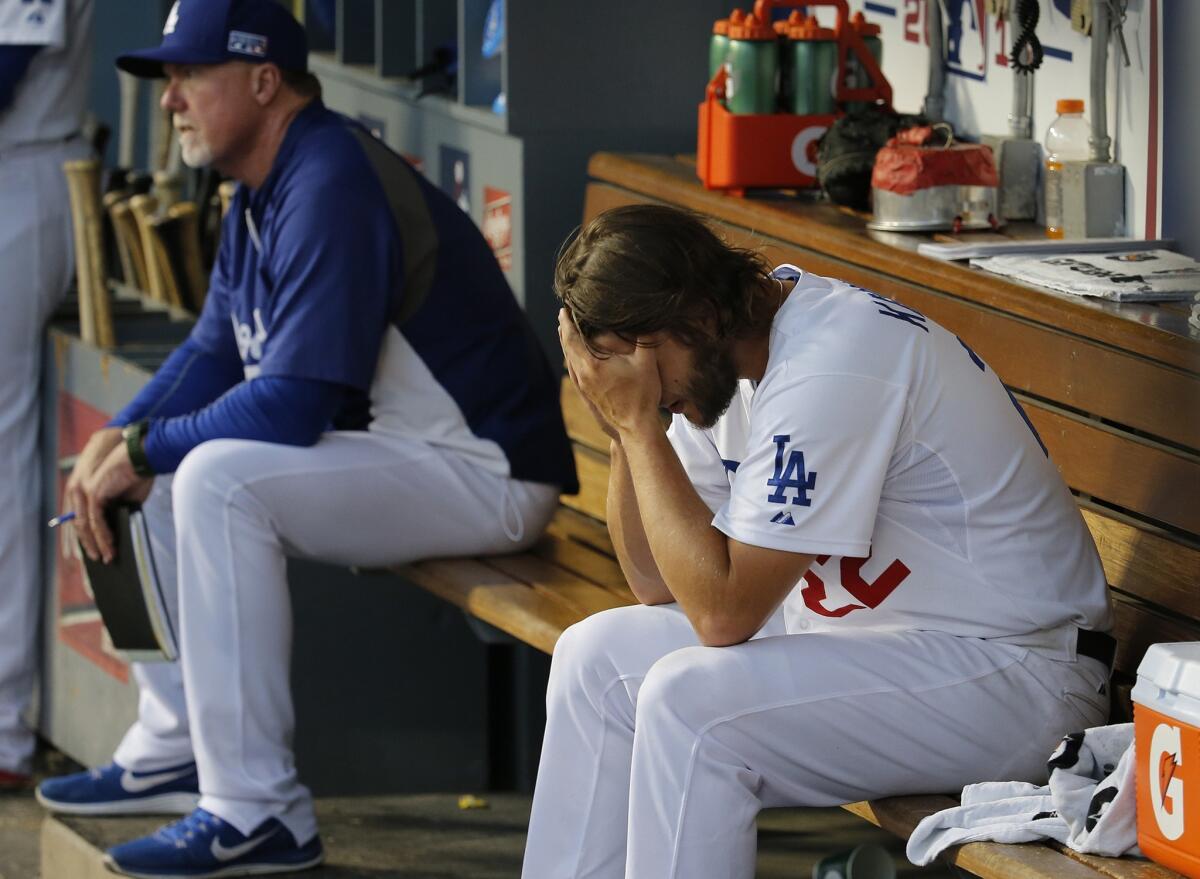 Dodgers ace Clayton Kershaw sits on the bench near hitting coach Mark McGwire after getting knocked out of the game by the Cardinals during an eight-run seventh inning.