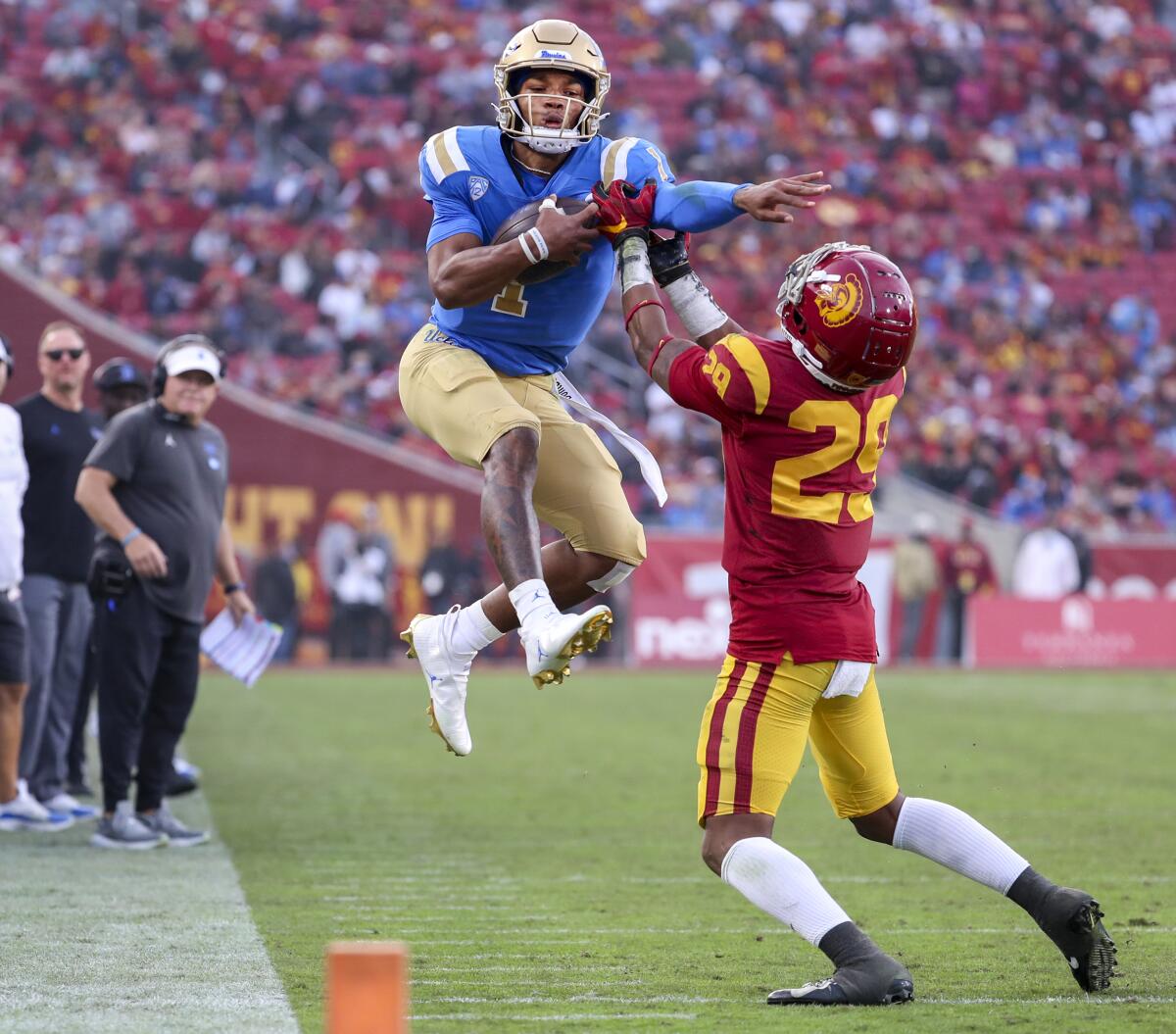 UCLA quarterback Dorian Thompson-Robinson leaps in an attempt to get past USC safety Xavion Alford
