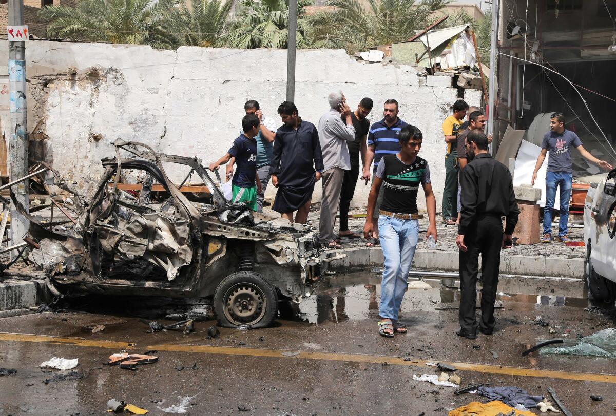 Civilians and security forces inspect the scene of a car bombing in Baghdad's Karrada neighborhood.