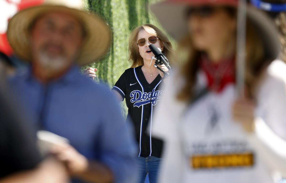 A woman in a Dodgers jersey talks into a microphone.