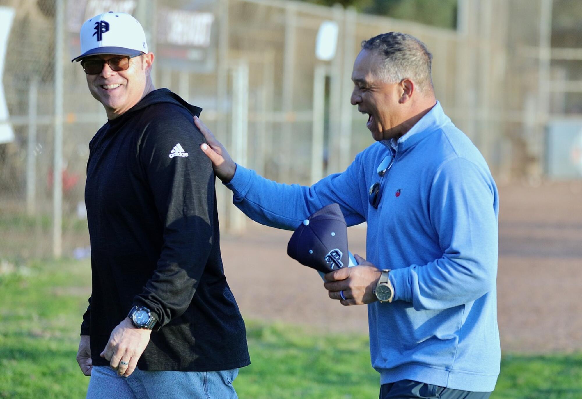 Dodgers yöneticisi Dave Roberts, bir sahadan çıkarken Palisades Charter High Beyzbol Koçu Mike Voelkel ile güler.