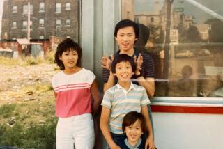 A family of four kids and teenagers standing in front a restaurant storefront.